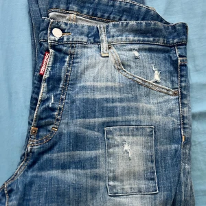 Dsquared2 blå slitna jeans, stl 52 - Riktigt snygga blå jeans från Dsquared2 med slitningar, patchade detaljer och coola trasiga partier. Jeansen passar för nån som har storlek m-L mycket fina använt 2 3 ggr tyvär inget kvitto. De är ett par äkta dsqured!