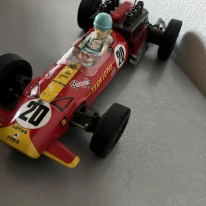 Retro Vintage race bil För Samlaren 29 cm lång - Bilderna visar en leksaksbil i form av en klassisk Formel 1-bil med märkningarna 'Team Lotus', nummer 20 och detaljer som förare och motor. Det är ingen bok på bilderna, utan en samlarleksak för bil- och motorsportentusiaster.