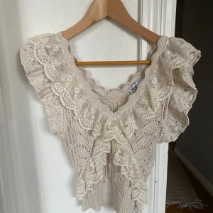 Beige stickad blus med spetsdetaljer från Zara - Superfin beige stickad blus från Zara med v-ringning och volangprydda spetsdetaljer framtill och längs ärmarna. Perfekt för dig som gillar romantisk och bohemisk stil.