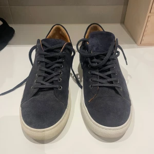Mörkblå mockasneakers med vit sula - Snygga skor från human scales, storlek 44. Använda en gång. Säljer pga av att de är för små. Ordinarie pris:1899kr Herbert Suede Sneakers från Human Scales tillverkade av 100 % slät kalvmocka med innerfoder i kalvskinn. Har gummisula för maximal komfort och hållbarhet.