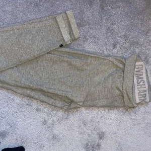 Gråa/gröna träningstights från Gymshark - Säljer ett par grå mjukisbyxor från Gymshark. Som inte längre kommer till användning, i bra skick. Strl S men passar även M