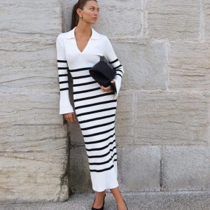 Vit och svart randig klänning från NA-KD - Snygg vit och svart randig klänning från NA-KD med ribbad struktur. Klänningen har en v-ringad krage och långa ärmar med en tight passform. Perfekt för en stilren look! Storlek S. Använd en gång.