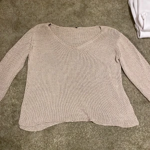 Beige stickad tröja med v-ringning - Säljer en beige stickad tröja med v-ringad hals. Tröjan har lång ärm och är lätt oversized i modellen. Perfekt för lager-på-lager och passar till det mesta.