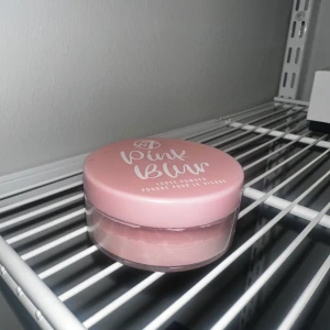 W7 Pink Blur Loose Powder - Säljer ett löspuder från W7 i färgen Pink Blur. Kommer i en rund burk med rosa lock och transparent underdel så du ser pudret. Perfekt för att fixera sminket och ge en mjuk finish.