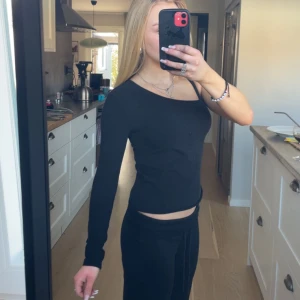Svart oneshoulder topp - Säljer en svart långärmad topp med oneshoulder-design. Snygg och enkel modell som passar perfekt till många olika outfits. Mjuk och stretchig i materialet för en bekväm passform.