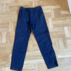 Mörkblå linnebyxor från Uniqlo - Säljer ett par mörkblå linnebyxor från Uniqlo i storlek S. Byxorna har rak passform, sidfickor och resår baktill i midjan för extra komfort. Perfekta för varmare dagar tack vare materialblandningen av linne och bomull.