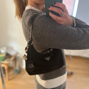 Svart axelväska från Prada - INTRESSEKOLL!!! Funderar på att sälja min älskade Prada väska!!! Den är klassisk svart med silverfärgad dragkedja och ikonisk trekantig logga framtill. Bra skick!! Köpt på Prada i Stockholm!! De finns kvitto, bevis etc. 
