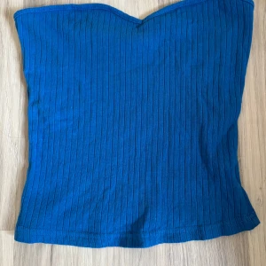 Blå ribbad tubtopp från shein - Säljer en blå ribbad tubtopp från shein Toppen är ärmlös och har en snygg hjärtformad överkant. Perfekt att styla till jeans eller kjol för en trendig look.