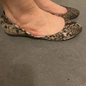 Ormskinnsmönstrade ballerinaskor från Claudia Ghizzani - Säljer ett par ballerinaskor från Claudia Ghizzani med ormskinnsmönster i beige, brunt De är även i ÄKTA SKIN och svart. Skorna har rund tå och platt sula,. De är i storlek 39 jätte sköna ! 