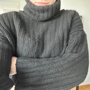 Svart croppad stickad polotröja - Mysig svart stickad polotröja med croppad passform och breda ribbade detaljer. Tröjan har långa ärmar och en hög, tjock polokrage som ger en cool och avslappnad look. Storlek S använd 1 gång. 