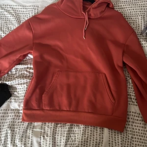 Korallfärgad hoodie från SHEIN - Säljer en korallfärgad hoodie från SHEIN i storlek S. Tröjan har en klassisk huva med dragsko och en stor magficka framtill. Tillverkad i mjuk polyester som är skön mot huden. Perfekt för dig som gillar en enkel och stilren look.