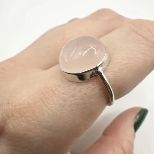 Handgjord rosenkvartsring i silverplätering - sten för kärlek och harmoni  - Elegant ring med cabochonslipad rosenkvarts infattad i silverplätering. Handgjord med omsorg – varje exemplar bär sin egen karaktär. Rosenkvarts är känd som själens och kärlekens sten, och sägs främja lugn, balans och självkärlek.  Ringen har en tidlös design som gör sig lika bra till vardags som vid fest. Perfekt att bära ensam eller matcha med andra ringar för en personlig look.  • Storlek: ca 18, 18 mm • Material: Silverplätering & rosenkvarts • Skick: Mycket fint • Ursprung: Handgjord  