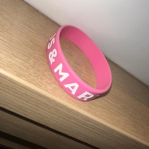 Rosa silikonarmband med vit text - Säljer ett rosa armband i silikon med vit text. Perfekt accessoar för att addera lite färg till din stil. Armbandet är flexibelt och bekvämt att bära hela dagen.