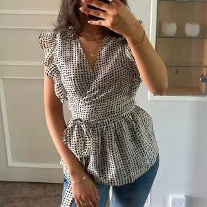 Blus - Jättefin vit och svart prickig blus med knyte och volanger, aldrig använd, nypris 600kr, passar både xs/s