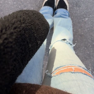 Ljusblå jeans med slitningar och röd söm - Säljer ett par ljusblå jeans med slitningar på knäet, gjort hålen själv och använt byxorna max 2 gånger, säljer dom pga att jag inte tycker att byxorna passar min kroppsform 