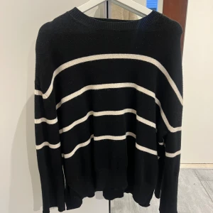 Svart stickad tröja med vita ränder från BikBok - Säljer en svart stickad tröja från BikBok med vita  ränder. Tröjan har rund halsringning och långa ärmar. 
