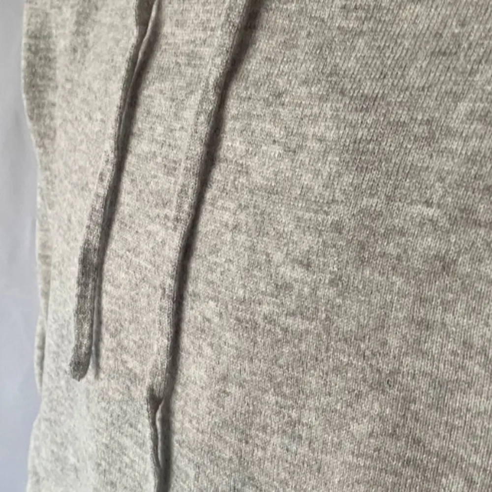 Säljer en stilren grå merino hoodie. Tröjan har en klassisk design med huva samt långa ärmar. Perfekt för en avslappnad look.. Neuletakit & Villapaidat.