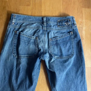 Diesel blå jeans - y2k - Säljer ett par lågmidjade diesel jeans i klassisk blå tvätt med raka ben och coola detaljer. I lappen står det att jeansen är st 14 men skulle säga att det i svensk storlek är 34.