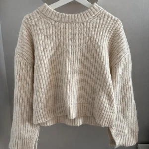 Stickad tröja  - En beige stickad tröja från Gina tricot i storlek S, slits på armarna och vid sidan 