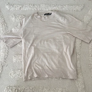 Beige stickad tröja från lager157 - Snygg beige stickad tröja från lager157 i storlek XS. Tröjan har korta ärmar och ribbade detaljer vid hals, ärmslut och nederkant. Perfekt för dig som gillar enkel och clean stil med en neutral färg som passar till allt.
