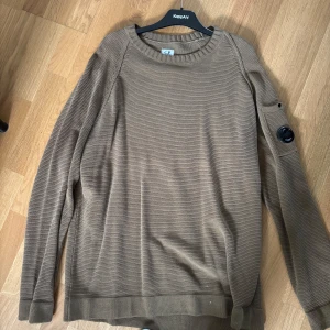 Brun stickad tröja från CP Company - Säljer en brun stickad tröja från CP Company med ribbade muddar och rund hals. 