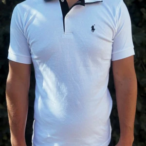 Vit Polo Ralph Lauren t-shirt M - Vit t-shirt från Polo Ralph Lauren med klassisk svart krage och knappslå. Ikonisk broderad logga på bröstet. T-shirten har korta ärmar och är gjord i mjuk bomull. Snygg passform som sitter normalt och passar perfekt till jeans eller shorts.                                                                                                                                                                               Nypris: 1499kr GORILLAPRIZE:635kr       Skick:10/10 oöppnad         KVITTO MEDKOMMER