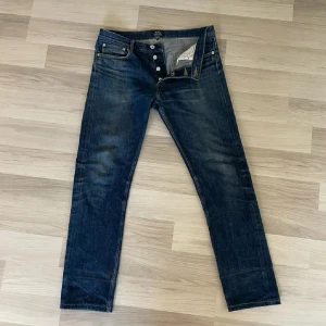 A.P.C. Petit Standard jeans blå - Säljer ett par klassiska A.P.C. Petit Standard jeans i mörkblå denim. Modellen har raka ben, fem fickor och knappgylf. Snyggt slitna detaljer och orange sömmar ger en clean look. Perfekta för dig som gillar minimalistisk stil.
