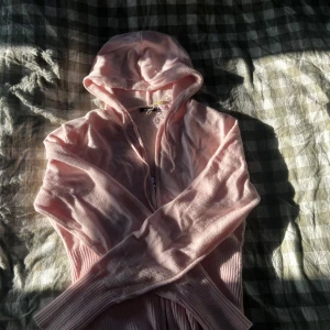 Ljusrosa hoodie från Gina Tricot - Mysig ljusrosa hoodie från Gina Tricot med dragkedja framtill och huva med snörning. Tröjan har långa ärmar och breda ribbade muddar vid ärmslut och nederkant. Perfekt för en chill och avslappnad stil. Endast använd fåtal gånger