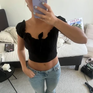 Svart söt topp - Säljer denna gulliga, korta toppen från Boohoo❤️ Tröjan är knappt använd och är i toppskick, den har inga tecken på användning 💕 Den har en knytning där framme och har söta volangdetaljer