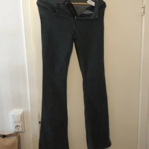 Mörkgrå bootcut jeans tall M - Snygga mörkblå jeans med bootcut-modell och klassisk femficksdesign. Jeansen har normal midja och är tillverkade i ett mjukt denimtyg som sitter skönt hela dagen. Perfekta för dig som gillar en tidlös och avslappnad stil.