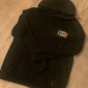 Svart hoodie från Vans - Svart hoodie från Vans. Stort tryck på ryggen och litet frm. Använd fåtal gånger men ser ny ut, inga defekter och fortfarande mjuk innuti. Klassisk huva. Den är Large barnstorlek men som en Xs.