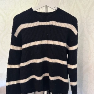 Svartvit randig stickad tröja H&M - Säljer en svart stickad tröja från H&M i storlek XS med breda vita ränder. Tröjan har ribbad struktur, rund halsringning och långa ärmar. Perfekt för dig som gillar en chill och stilren look.