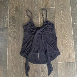 Svart linnetopp med knyt från Gina Tricot - Säljer en svart linnetopp från Gina Tricot i storlek S. Toppen har tunna axelband och en snygg knytning framtill. Jätte skönt material.