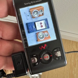 Nyskick orginal Sony Ericsson W595 -  Sony Ericsson W595 mobiltelefon med tillhörande batteri  Perfekt för retro-entusiaster eller samlare av klassisk teknik.