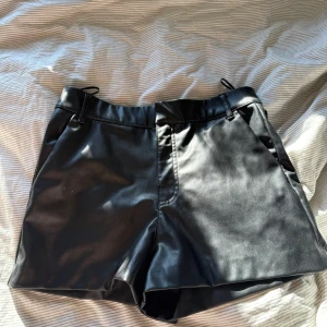 Svarta skinnshorts från Zara - Snygga svarta shorts från Zara i skinnimitation med midwaist passform. De har bälteshällor och klassisk design utan synliga detaljer, vilket gör dem riktigt stilrena. 