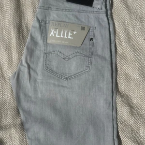 Replay X-Lite+ ljusgrå jeans, strl 30 - Säljer ett par Replay X-Lite+ jeans i en snygg ljusgrå färg. Modellen heter Rocco och har comfort fit, vilket ger en avslappnad känsla. Jeansen är tillverkade i ultralätt denim och har klassiska fickor med Replay-detaljer. Perfekta för dig som gillar stilrena och bekväma jeans.