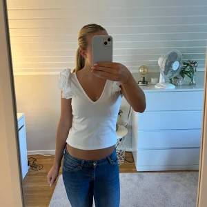 Vit v-ringad topp med volangärmar Zara - Supersöt vit topp från Zara Trafaluc med djup v-ringning och axelband med volanger. Croppad modell som sitter snyggt till jeans eller kjol. Volangdetaljerna på axlarna ger en extra touch till looken. I storlek S, men jag har sytt in den på sidorna för en tightare passform, så jag skulle mer säga att den är i XS. Det går också lätt att sprätta upp då jag inte har klippt bort tyget efter jag sydde in toppen. Har en liten fläck men är inget som man tänker på, annars i väldigt fint skick. 💕💕