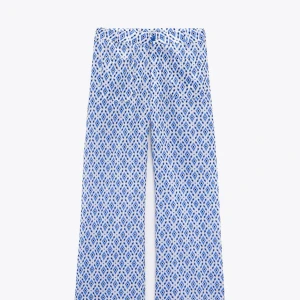 Mönstrade vida byxor från Zara XS - Säljer ett par vita byxor från Zara i storlek XS med blått och vitt mönster. Byxorna har rak och vid passform. Jag är 170cm lång och de sitter perfekt i längden