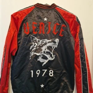 Diesel bomber jacka  - Snygg bomberjacka från Diesel i svart och rött som man kan vända ut & in på. Special Edition inköpt i New York. Artisten Wycleaf Jean hade en likadan på en utav sina konseter. Materialet är glansigt och känns lyxigt, perfekt för dig som vill sticka ut. Oversize storlek och använd vid 2 tillfällen. 