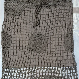 Grönt virkad kjol från Friendtex - Unik grön kortkjol från Friendtex i 100% bomull. Kjolen har ett virkat nätmönster med stora cirklar och knytband i midjan. Perfekt för dig som gillar boho-stil och vill sticka ut med coola detaljer.