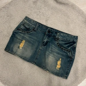 Blå jeanskjol  - Snygg blå jeanskjol från SWAG i kort modell med slitna detaljer och nitar på baksidan❤️ mått med bilder kommer snart!