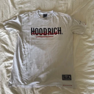 Vit t-shirt från Hoodrich med tryck Strl M/L - Vit t-shirt från Hoodrich i bomull med svart och rött tryck på bröstet och ryggen. Klassisk passform med korta ärmar och rund hals. Snygga detaljer som etikett nertill och texten 'FROM NOTHING TO SOMETHING' på ryggen. Perfekt för en streetwear-look. Passar både Medium och Large