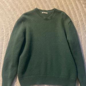 Grön stickad tröja från Zara - Mysig grön stickad tröja från Zara med rund halsringning och ribbade muddar vid ärmslut och nederkant. Perfekt för lager-på-lager och enkel att matcha med jeans eller kjol.