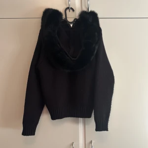 Alessa fur jacket  - Helt ny! Använd kanske 3 gånger💕Svart stickad hoodie från Alessa med dragkedja framtill och stor huva kantad med mjuk päls. Tröjan har ribbade muddar och en lite croppad passform. Perfekt för dig som vill ha en mysig och snygg look med extra edge. (Pris kan diskuteras)
