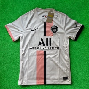 PSG vit och rosa fotbollströja Nike - Paris Saint-Germain fotbollströja i vitt med rosa och svart vertikal rand på framsidan. Tröjan har korta ärmar, svart Nike-logga och PSG-märke på bröstet. Tillverkad i lätt och ventilerande polyester, perfekt för träning eller match.