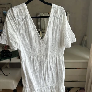 Vit klänning med broderie  - Superfin vit kort klänning i bomull med broderie. Perfekt för stranden eller till vardags! 