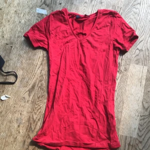 Röd v-ringad topp Park Lane XS - Enkel och snygg röd topp från Park Lane i storlek XS. Modellen har v-ringning och korta ärmar, perfekt för en chill och stilren look. Tillverkad i mjuk bomull som känns skön mot huden.