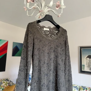 Grå spetsblus från Rosemunde Copenhagen - Supersnygg grå blus i genombruten spets med blommigt mönster. Långärmad och med rundad halsringning, perfekt för dig som gillar romantisk och detaljrik stil. Blusen är lätt och har en feminin vibe.