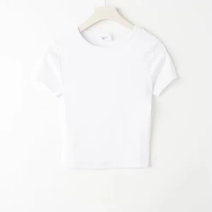Vit croppad t-shirt i bomull - En basic vit croppad t-shirt med rund hals och korta ärmar. Tillverkad i mjuk bomull, perfekt att matcha med jeans eller kjol för en clean look. Enkel och stilren design som funkar till allt.