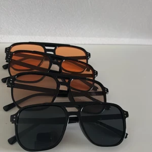 Fyra par retro pilotbågar solglasögon - Fyra par coola solglasögon i klassisk pilotmodell med svarta bågar. Två par har orangefärgade glas och två har bruna respektive mörkgrå glas. Alla har en stilren och tidlös vibe, perfekta för att lyfta din look i sommar. Finns nedrakade ute på min profil också 